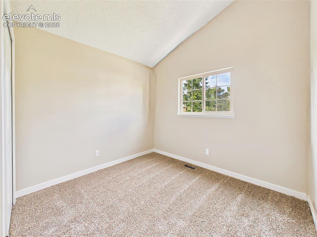 Image 30 of 50: Bright secondary bedroom featuring vaulted ceilings, new carpet, neutral fi