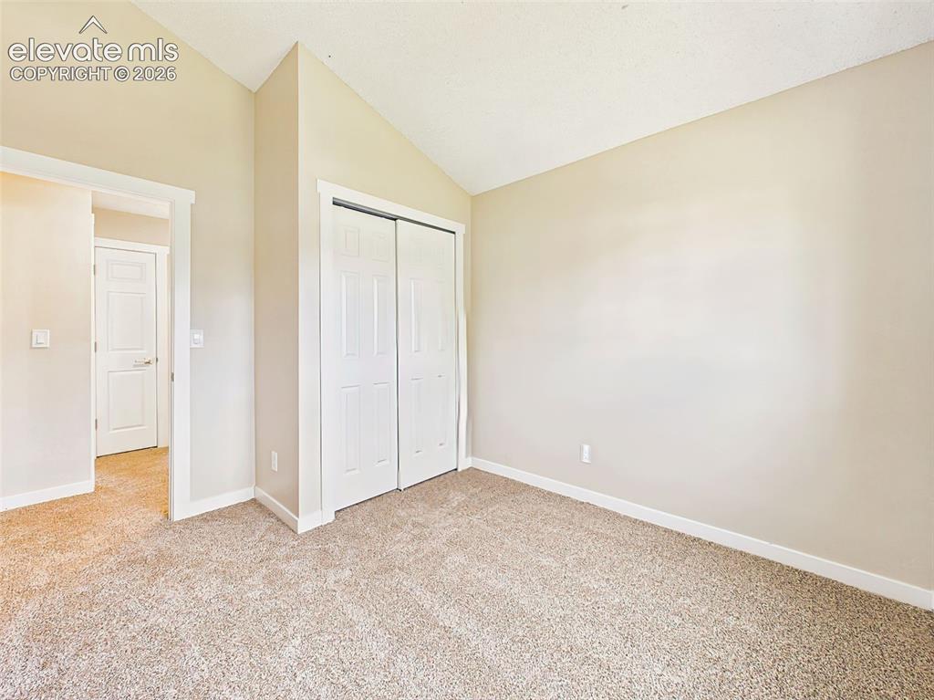 Image 31 of 50: Spacious secondary bedroom with vaulted ceilings, new carpet, neutral paint