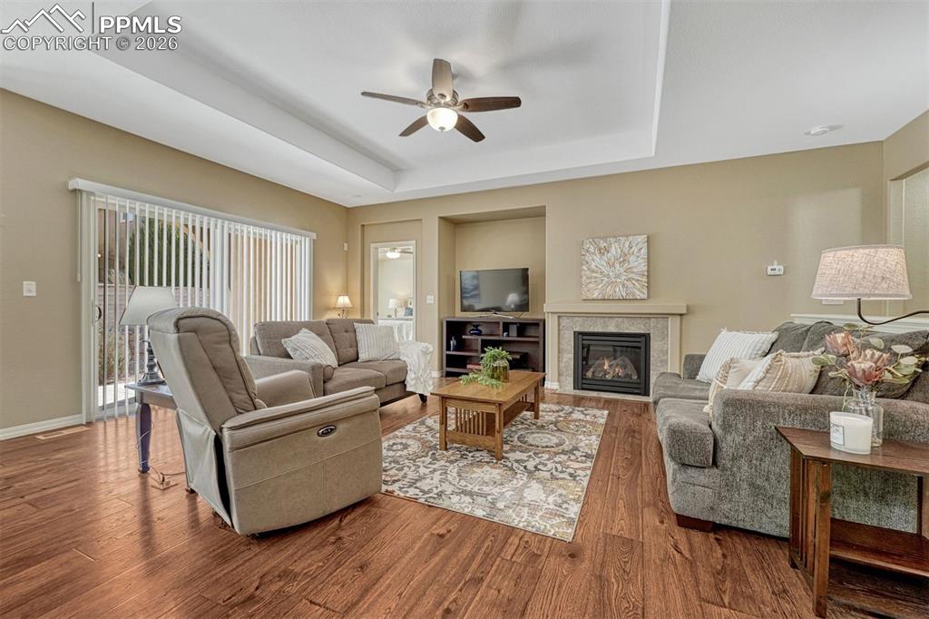 Image 24 of 41: Open living room with gas fireplace, trey ceiling, and sliding doors to the