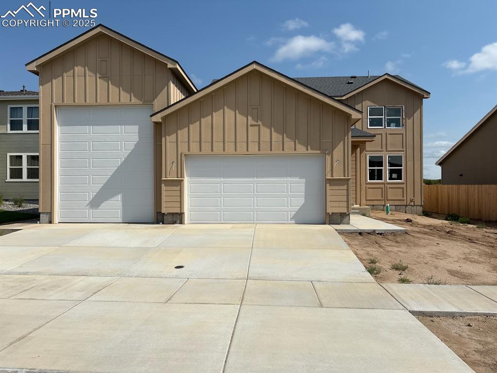 Caption: View of front of property with a garage, board and batten siding, and driveway