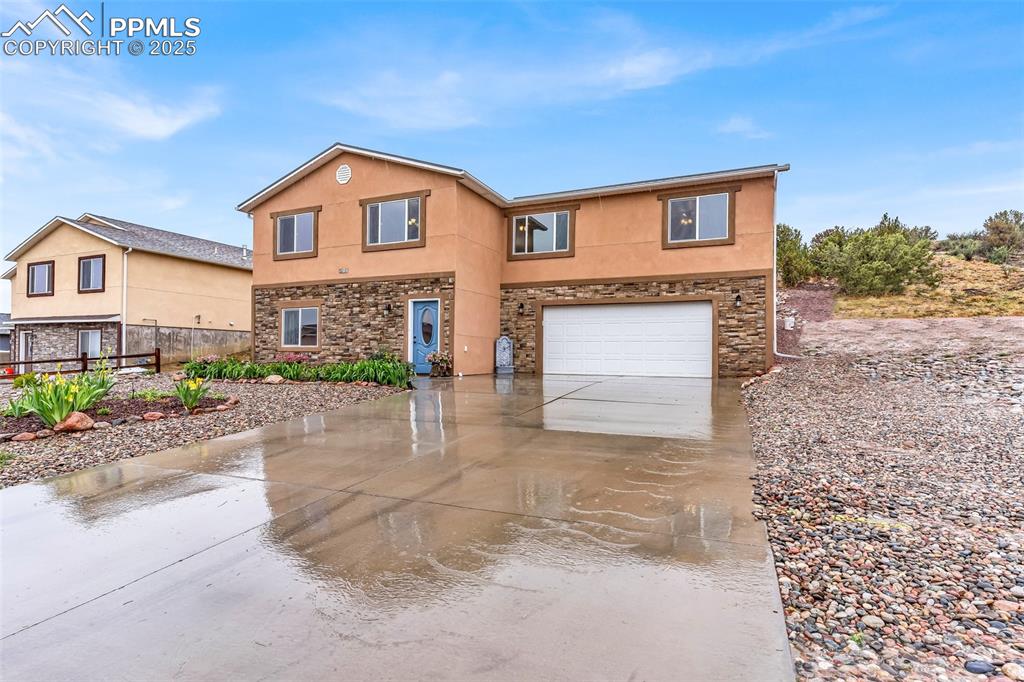 Image 3 of 50: Traditional-style house with stone siding, driveway, a garage, and stucco s