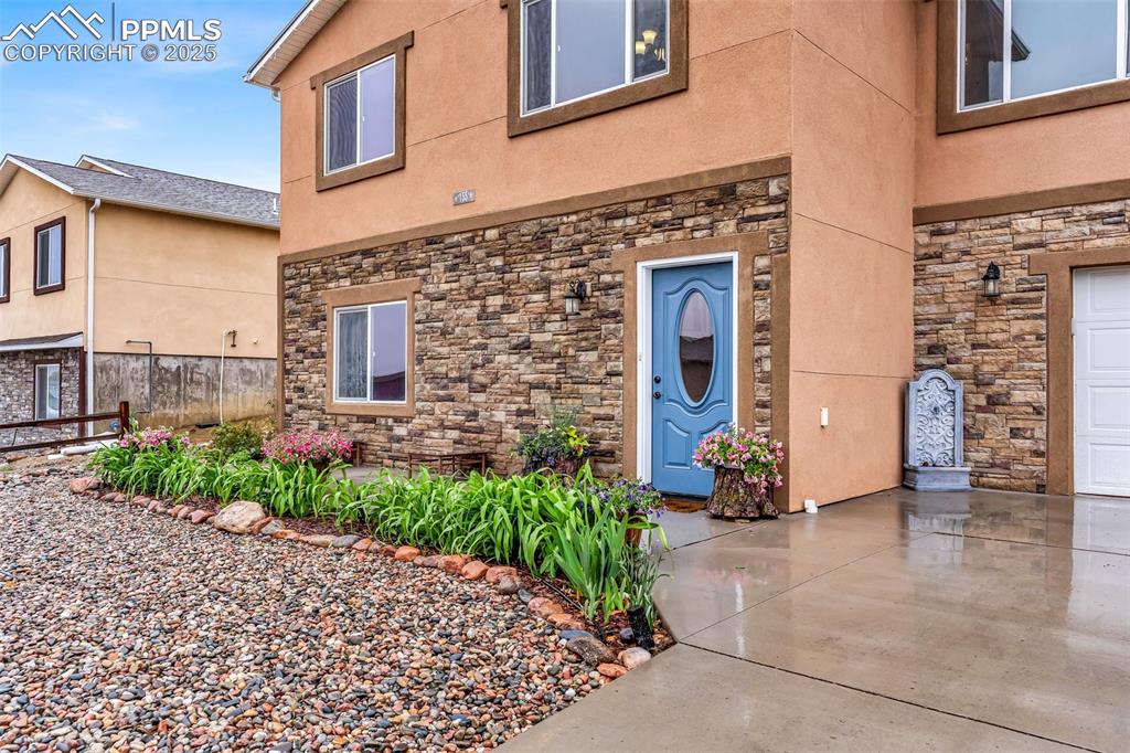 Image 4 of 50: Entrance to property featuring stone siding and stucco siding