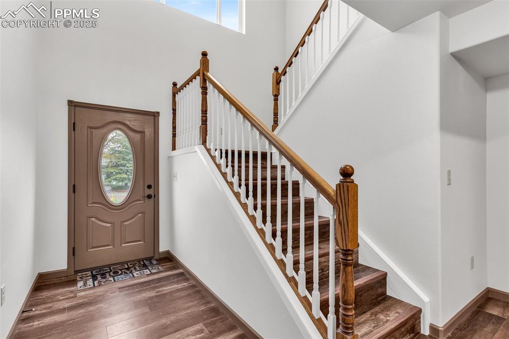 Image 5 of 50: Entryway featuring a high ceiling, wood finished floors, and stairs