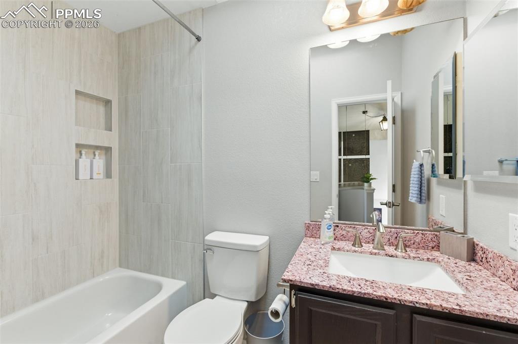 Image 28 of 44: The hall bath has beautiful tile surround and granite countertop and serves