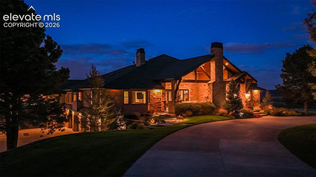 Image 1 of 50: Stone and wood-clad exterior with multiple chimneys, covered entry, and exp