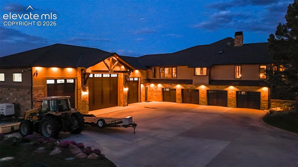 Image 3 of 50: Expansive multi-car garage with wood-finish doors, stone accents, and exter