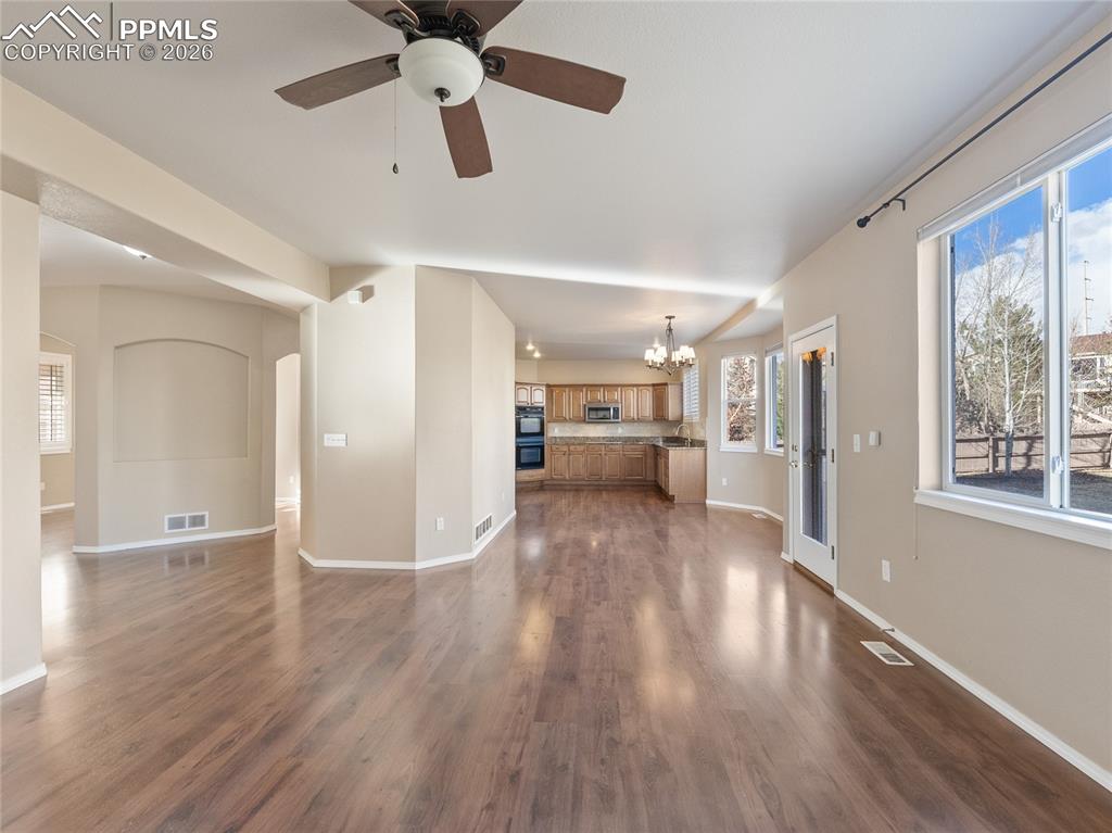 Image 14 of 46: Unfurnished living room featuring ceiling fan, a chandelier, dark wood-styl