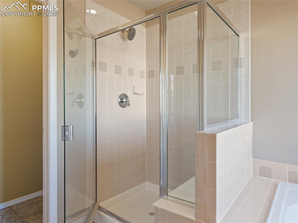 Image 24 of 46: Bathroom with a shower stall, a bath, and a textured wall