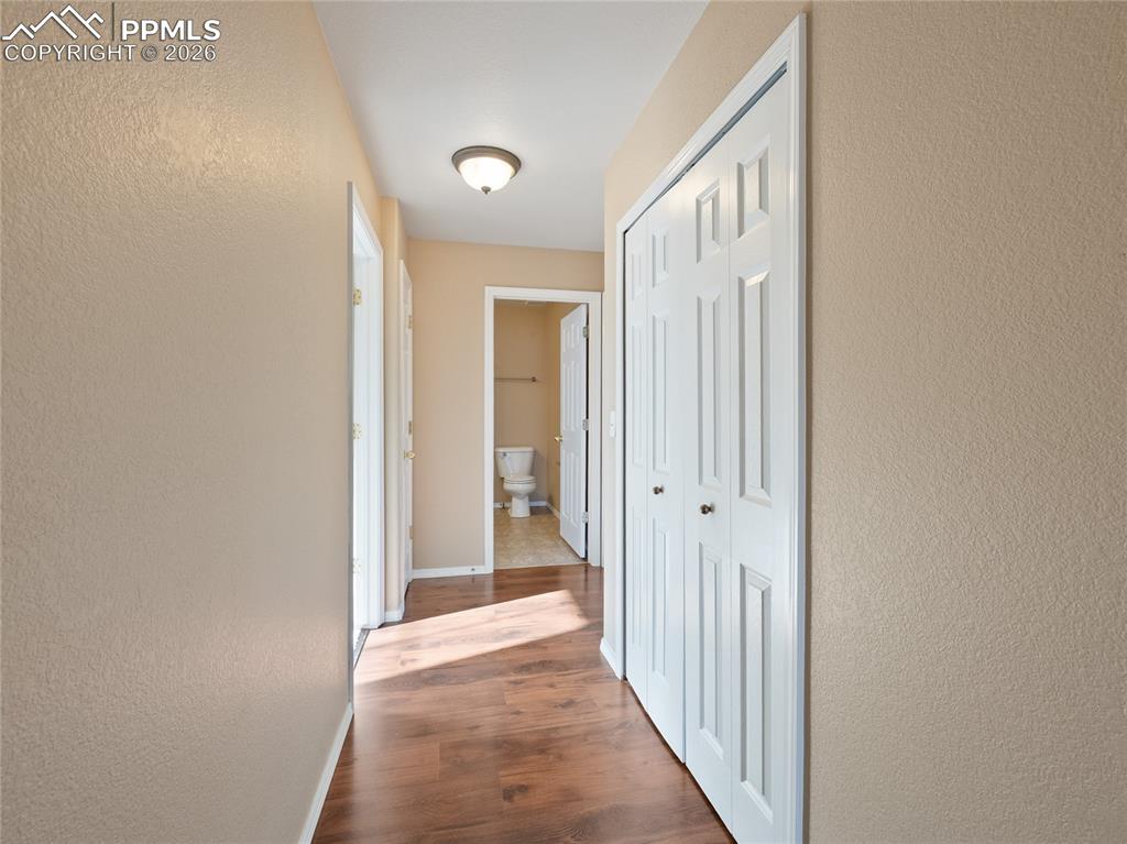 Image 26 of 46: Corridor with a textured wall and dark wood-type flooring