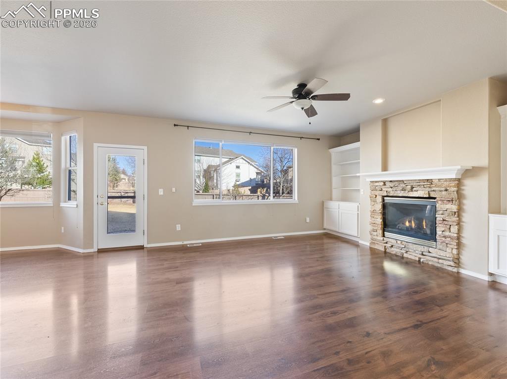 Image 3 of 46: Unfurnished living room with built in features, a ceiling fan, dark wood-ty