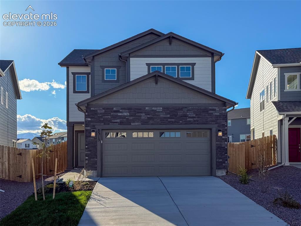 Caption: Modern two-story exterior with stone and siding facade, attached two-car garage, concrete driveway, 