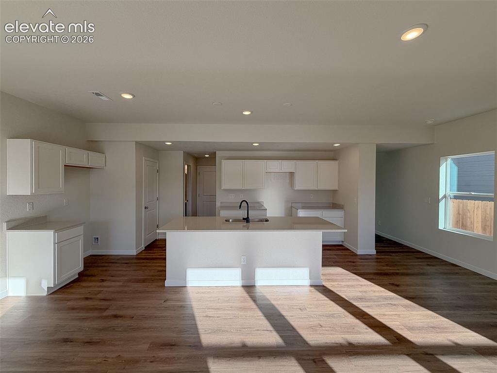 Image 10 of 34: Open-concept kitchen with white cabinetry, a center island, recessed lighti