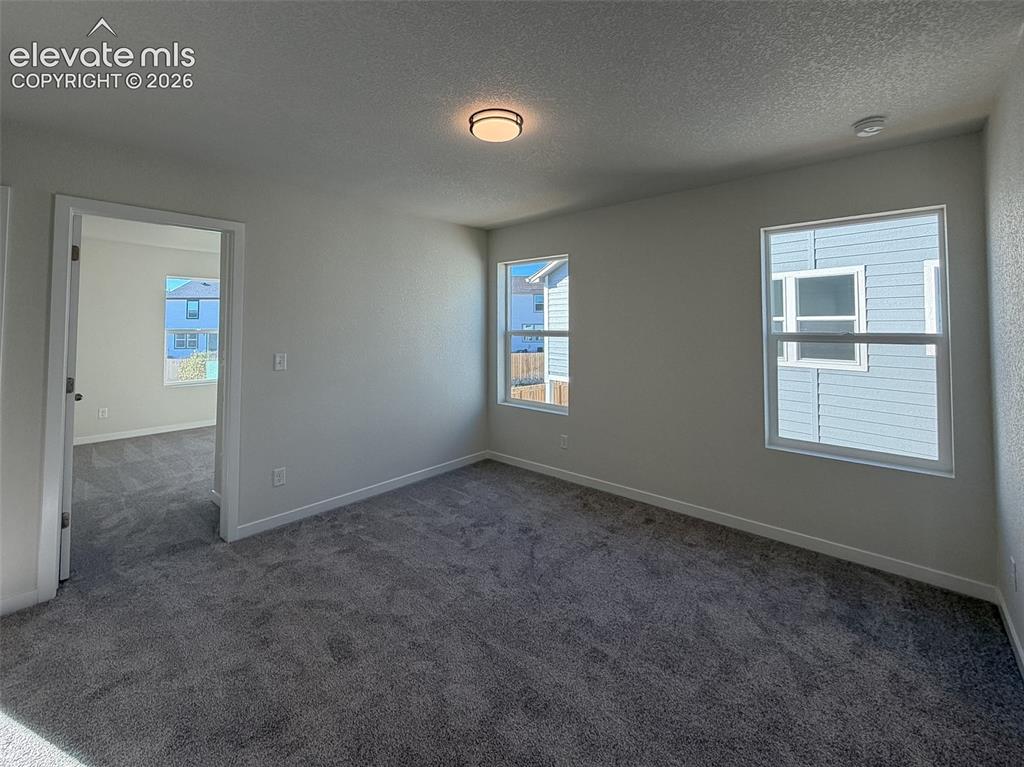 Image 14 of 34: Neutral gray wall finish, two large windows, gray carpet flooring, recessed
