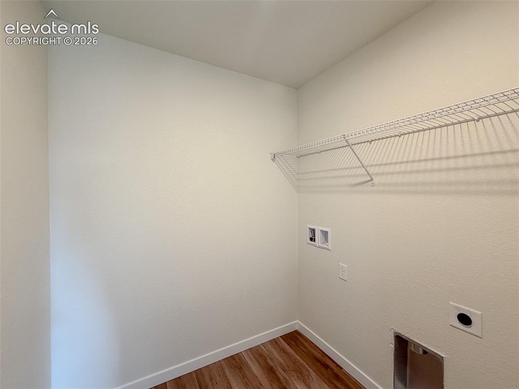 Image 31 of 34: Laundry area featuring wood-finish flooring, white painted walls, and a wir