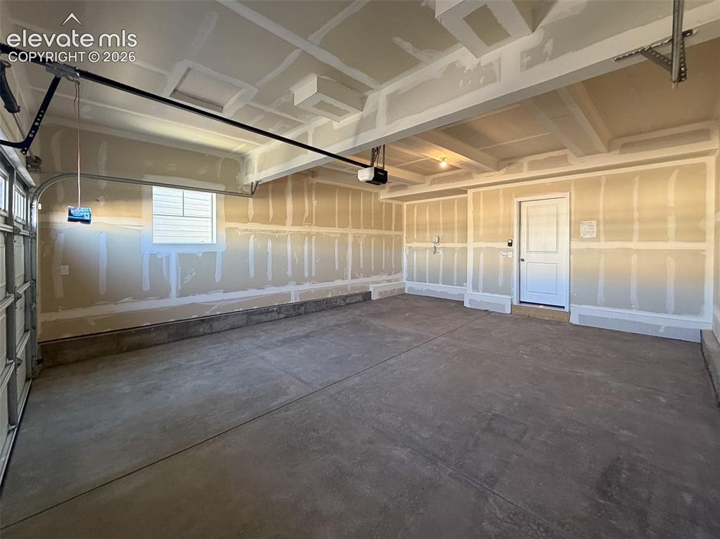 Image 32 of 34: Expansive garage featuring a concrete floor, built-in window, and a paneled