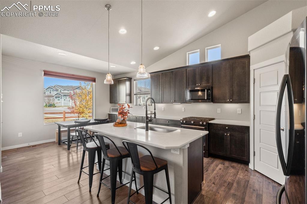 Image 11 of 48: Kitchen featuring lofted ceiling, freestanding refrigerator, dark brown cab
