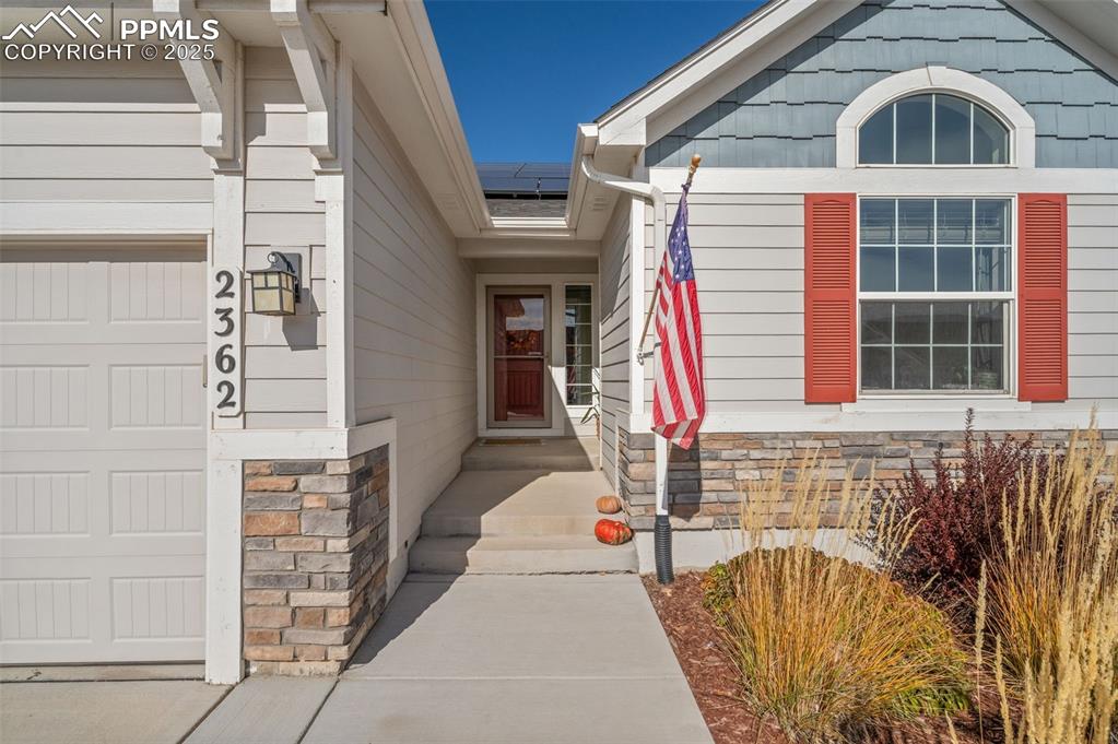 Image 2 of 48: Property entrance featuring roof mounted solar panels and stone siding