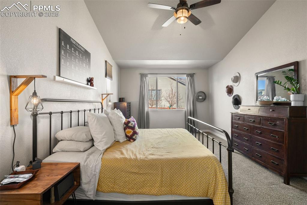Image 20 of 48: Carpeted bedroom with a ceiling fan and vaulted ceiling
