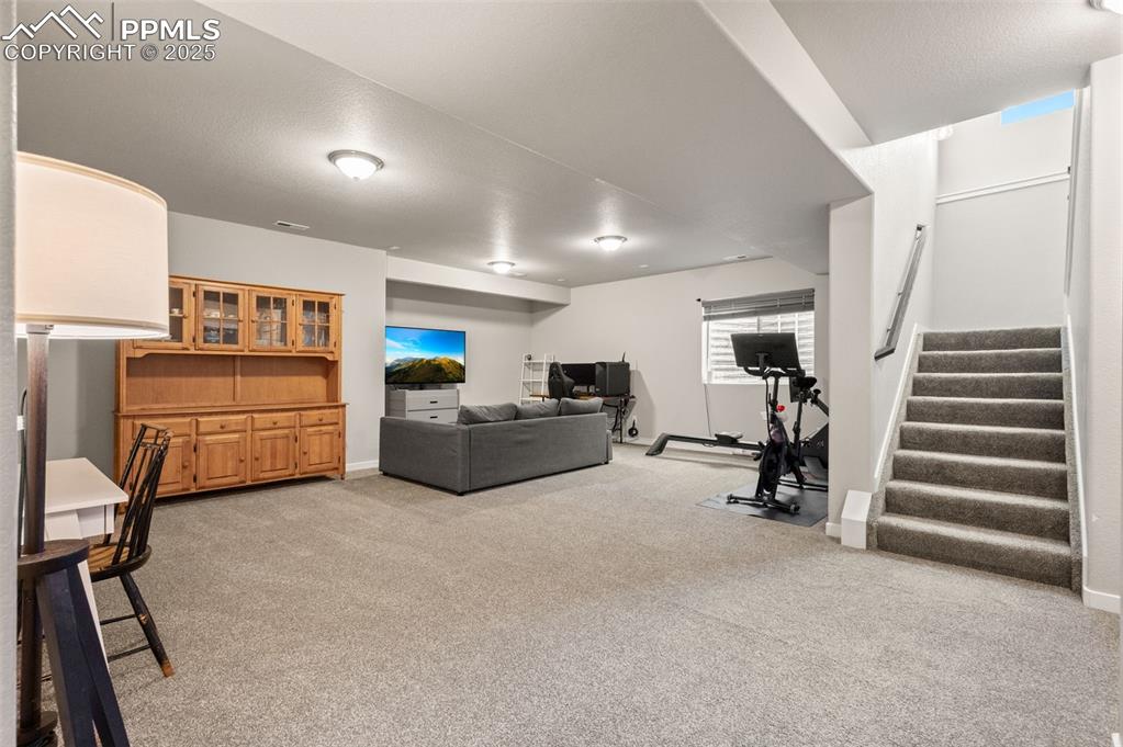 Image 27 of 48: Living area with light colored carpet and stairs