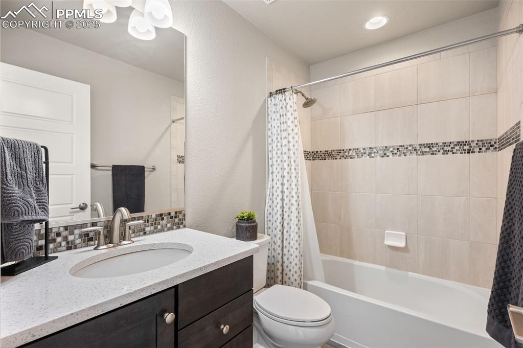 Image 34 of 48: Full bathroom featuring vanity, shower / tub combo with curtain, a textured