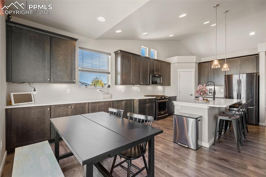 Image 9 of 48: Kitchen with dark brown cabinetry, a breakfast bar area, freestanding refri