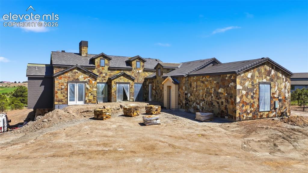 Image 1 of 5: Stone-clad exterior featuring multiple dormer windows and a prominent chimn