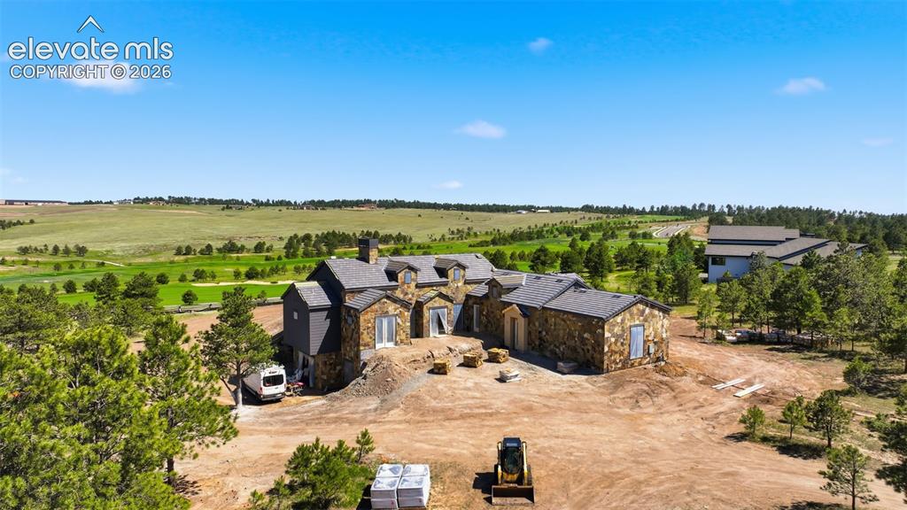 Image 4 of 5: Expansive stone-clad residence with multiple gables and a shingled roof