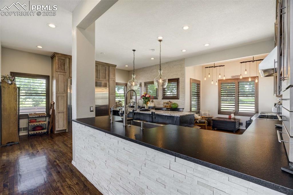 Image 10 of 50: Kitchen featuring hanging light fixtures, dark wood finished floors, dark s