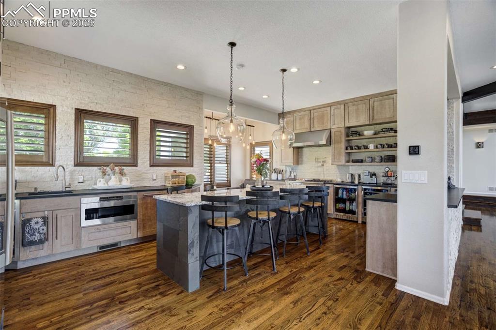Image 11 of 50: Kitchen featuring decorative backsplash, dark stone counters, a kitchen bar