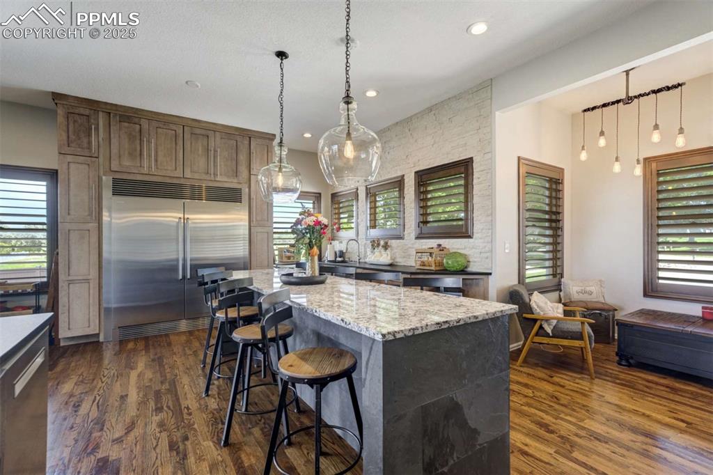 Image 14 of 50: Kitchen featuring dark stone counters, appliances with stainless steel fini