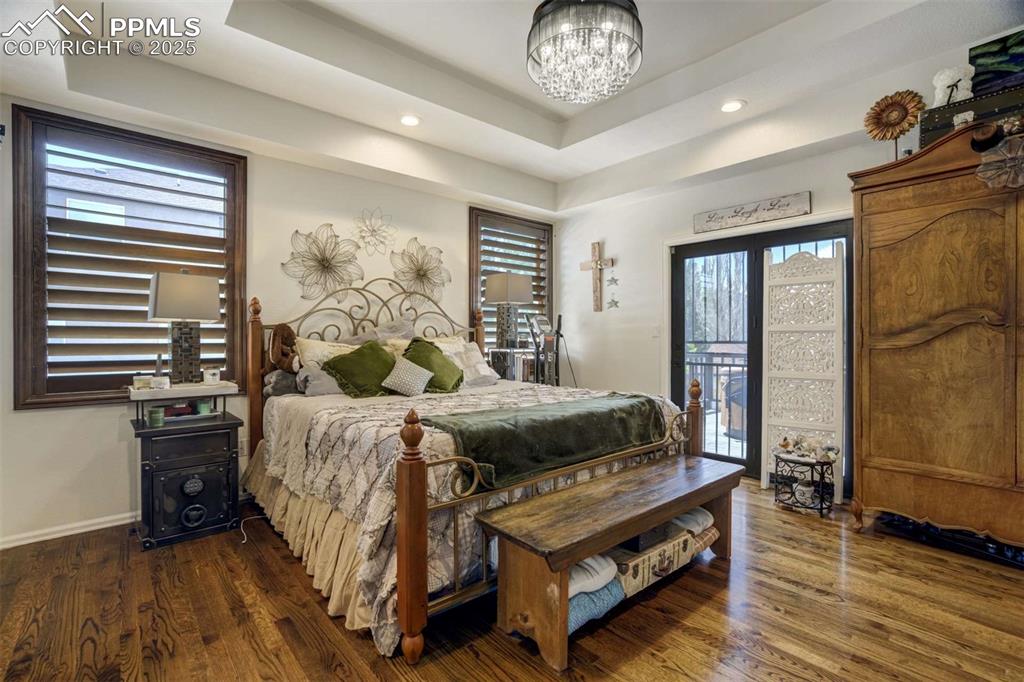 Image 20 of 50: Bedroom featuring access to exterior, dark wood-style floors, a chandelier,