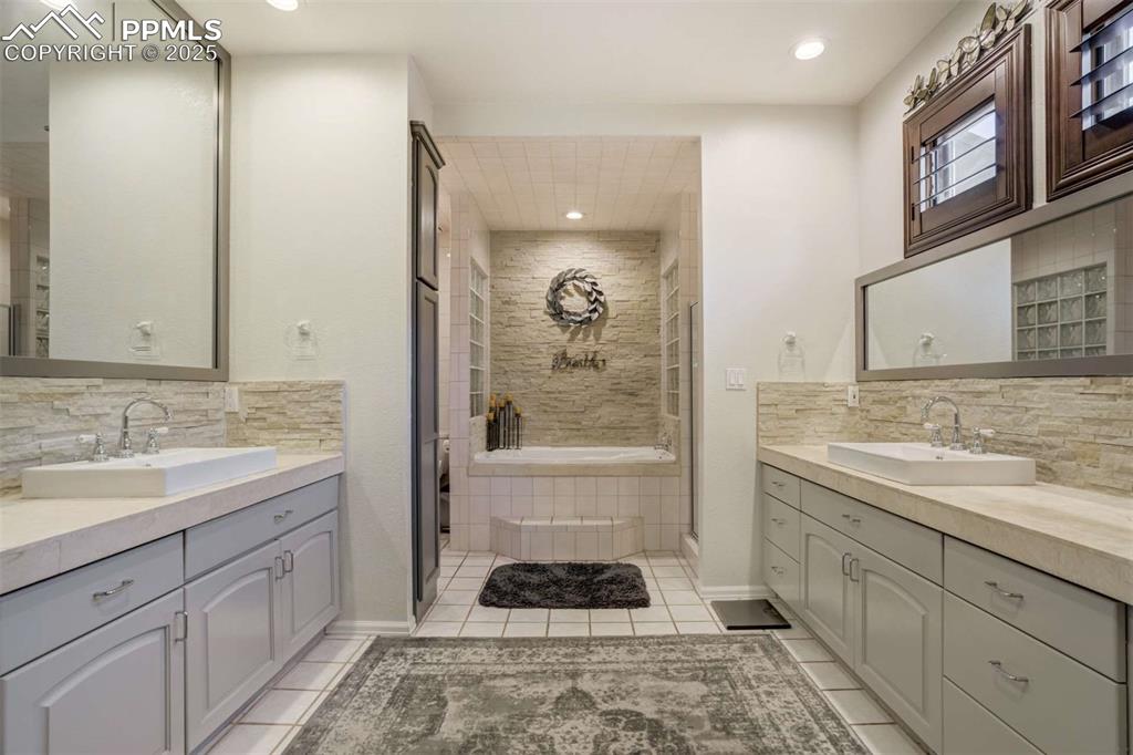 Image 22 of 50: Bathroom featuring backsplash, a garden tub, two vanities, recessed lightin