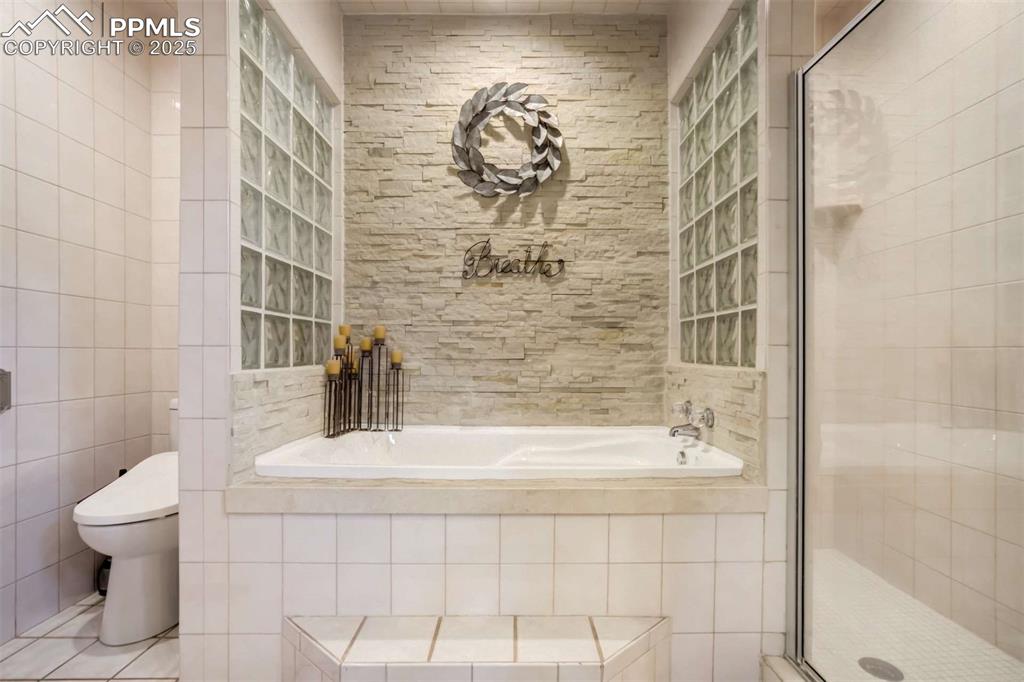 Image 23 of 50: Full bath with a bath, a shower stall, and tile walls