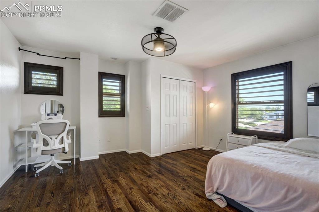 Image 24 of 50: Bedroom with multiple windows, dark wood finished floors, an office area, a