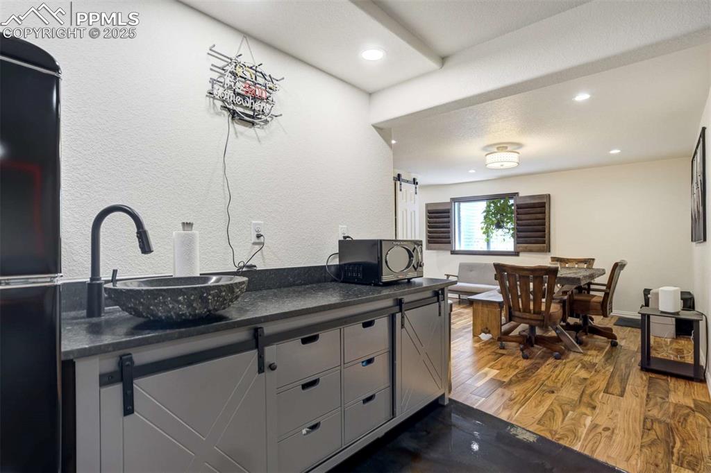 Image 33 of 50: Kitchen with a barn door, dark wood-style flooring, black appliances, reces