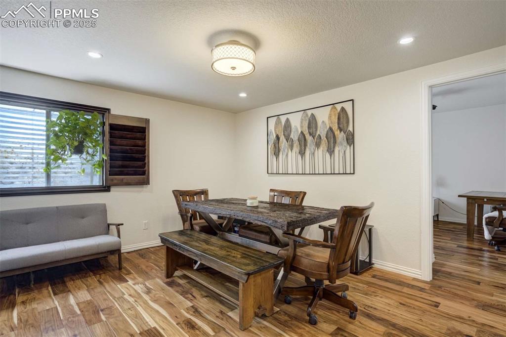 Image 34 of 50: Dining space featuring a textured ceiling, wood finished floors, and recess