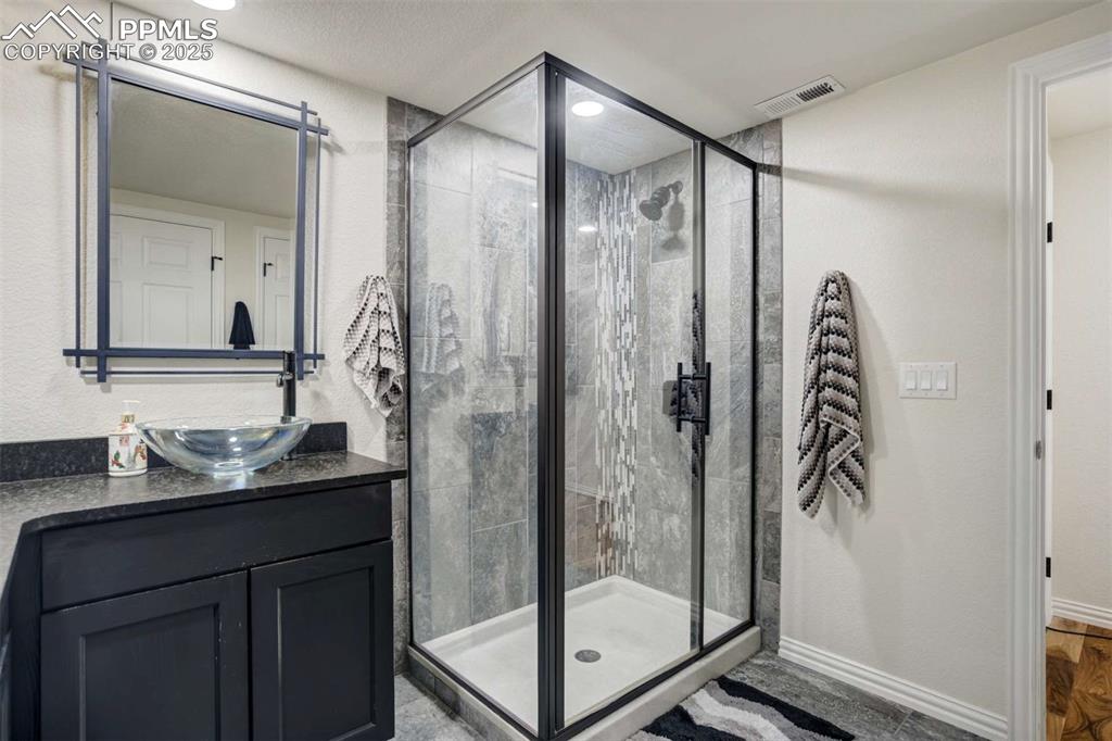Image 39 of 50: Bathroom with vanity, a shower stall, and a textured wall