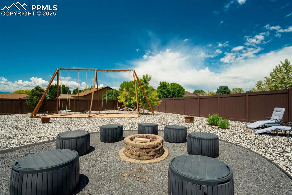Image 41 of 50: Fenced backyard featuring a patio area and a fire pit