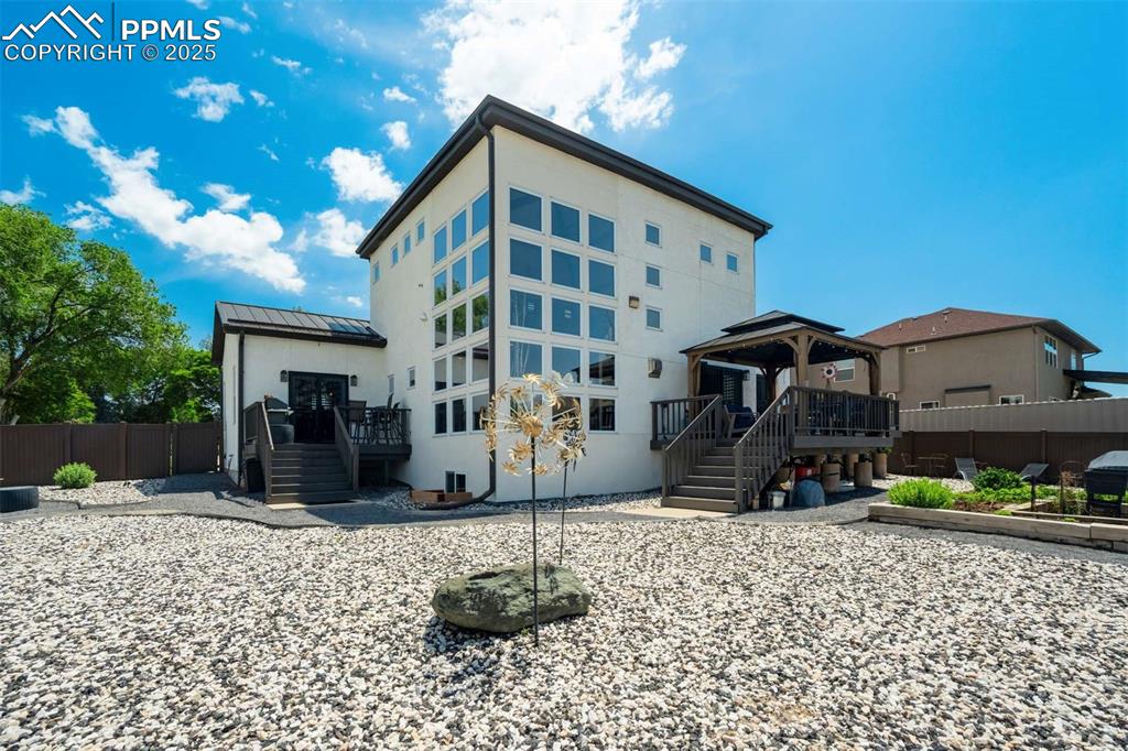 Image 42 of 50: Back of property with a gazebo, a wooden deck, a metal roof, a standing sea