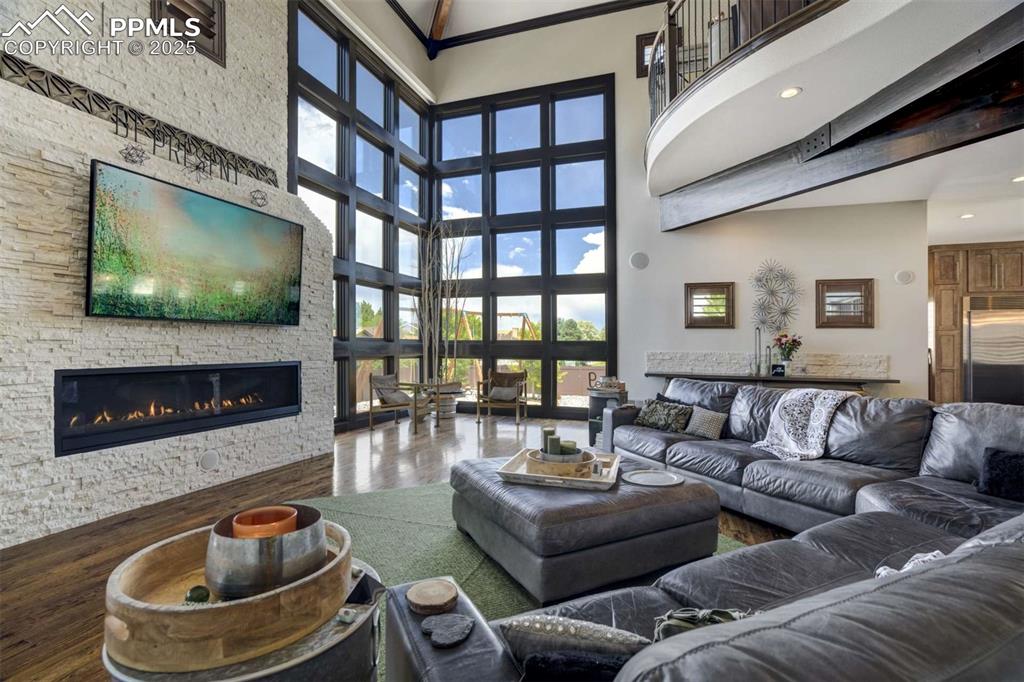 Image 5 of 50: Living area featuring a stone fireplace, a towering ceiling, wood finished