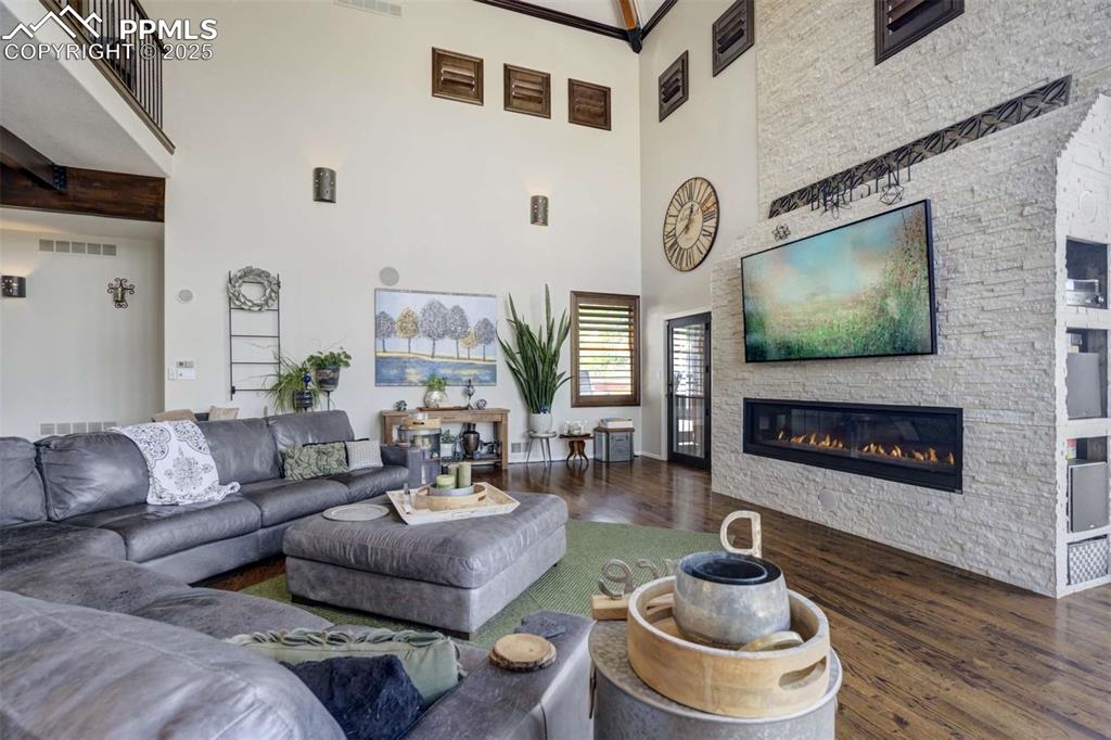 Image 6 of 50: Living area with dark wood-type flooring and a stone fireplace