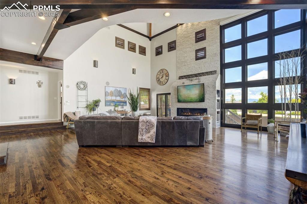 Image 7 of 50: Living area featuring dark wood-type flooring, a stone fireplace, and reces