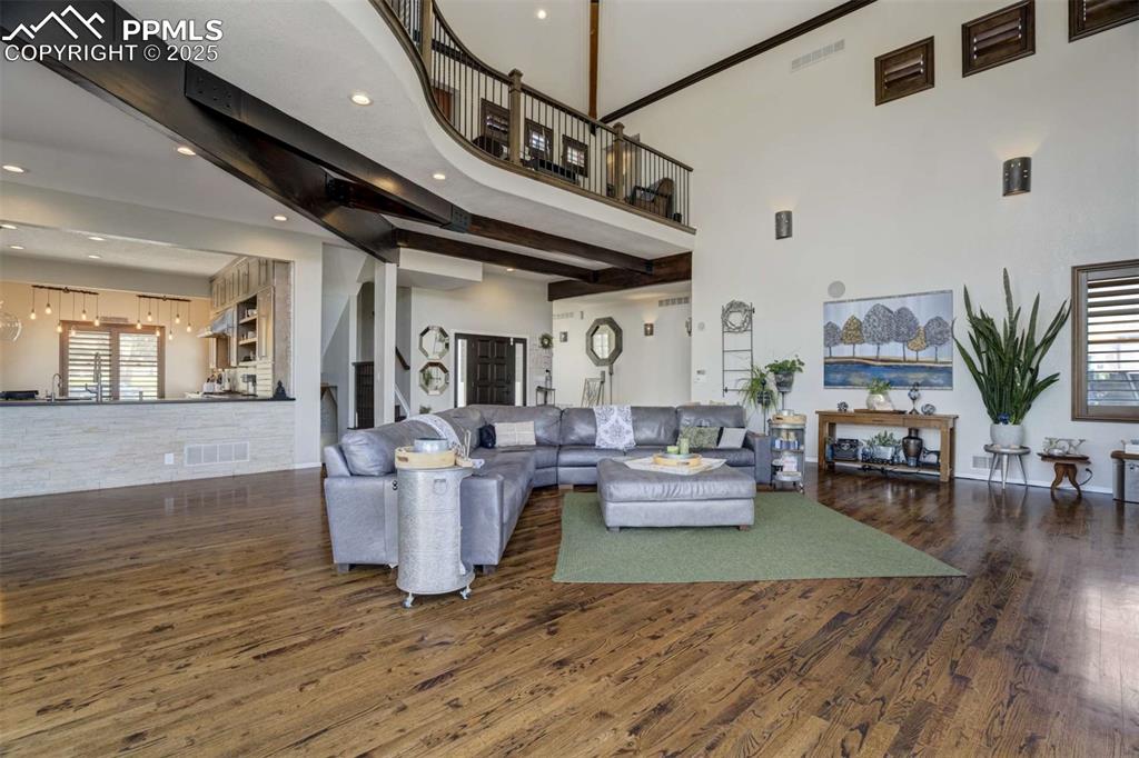 Image 8 of 50: Living area with dark wood-type flooring, stairway, recessed lighting, crow