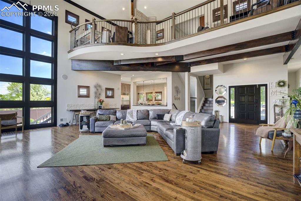 Image 9 of 50: Living room featuring dark wood-style floors, a high ceiling, stairway, ple
