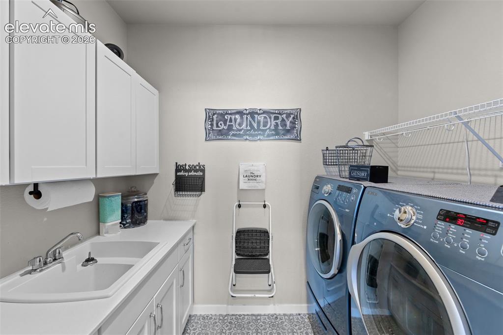 Image 13 of 32: Dedicated laundry room featuring white cabinetry, a utility sink with a chr