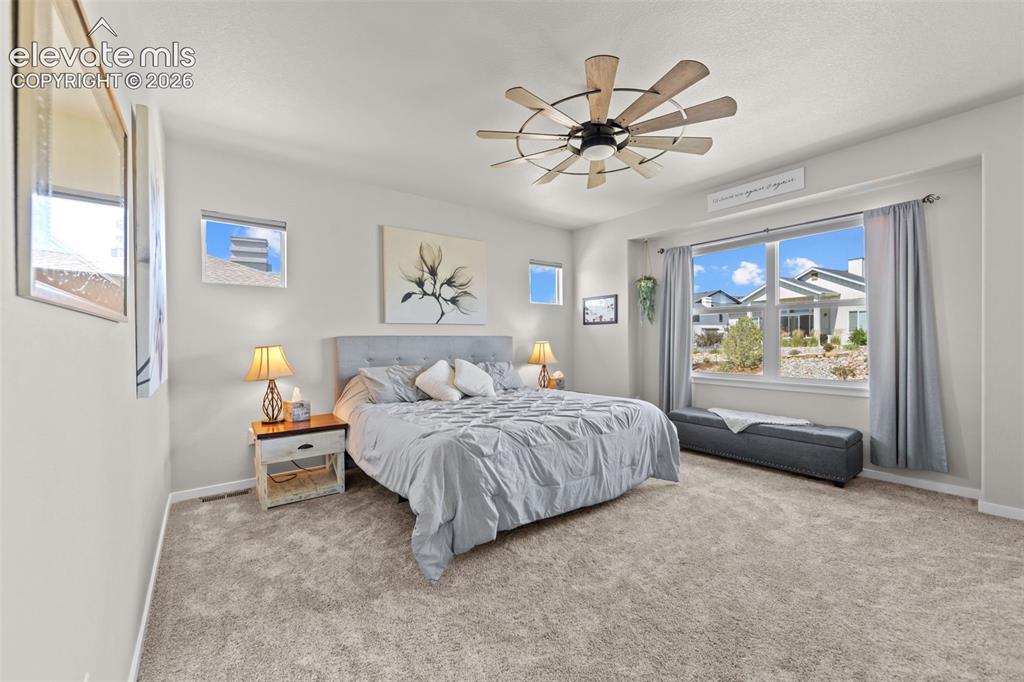Image 16 of 32: Carpeted bedroom featuring a large window, a ceiling fan, and recessed shel