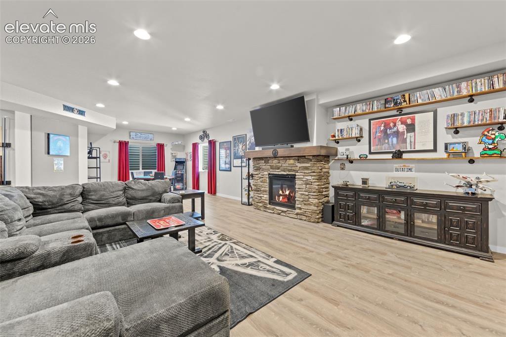 Image 18 of 32: Spacious entertainment room featuring a stone-clad fireplace with wood mant