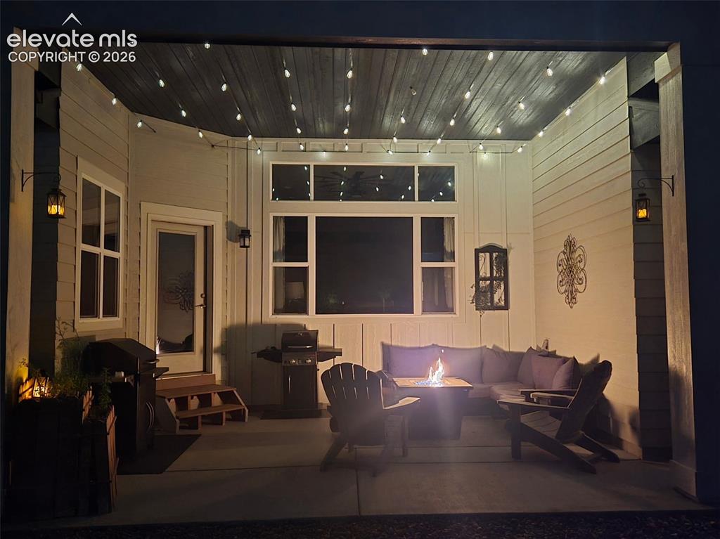 Image 26 of 32: Covered patio with a concrete surface at night featuring string lighting, a