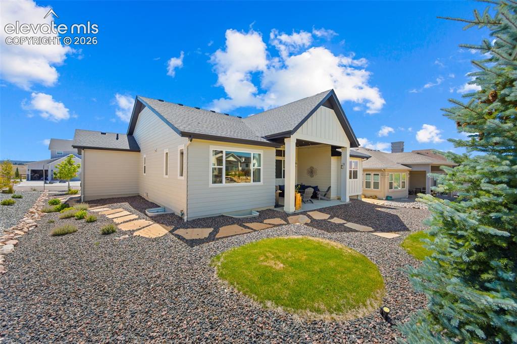 Image 28 of 32: Exterior rear elevation featuring a covered patio, landscaped grounds with