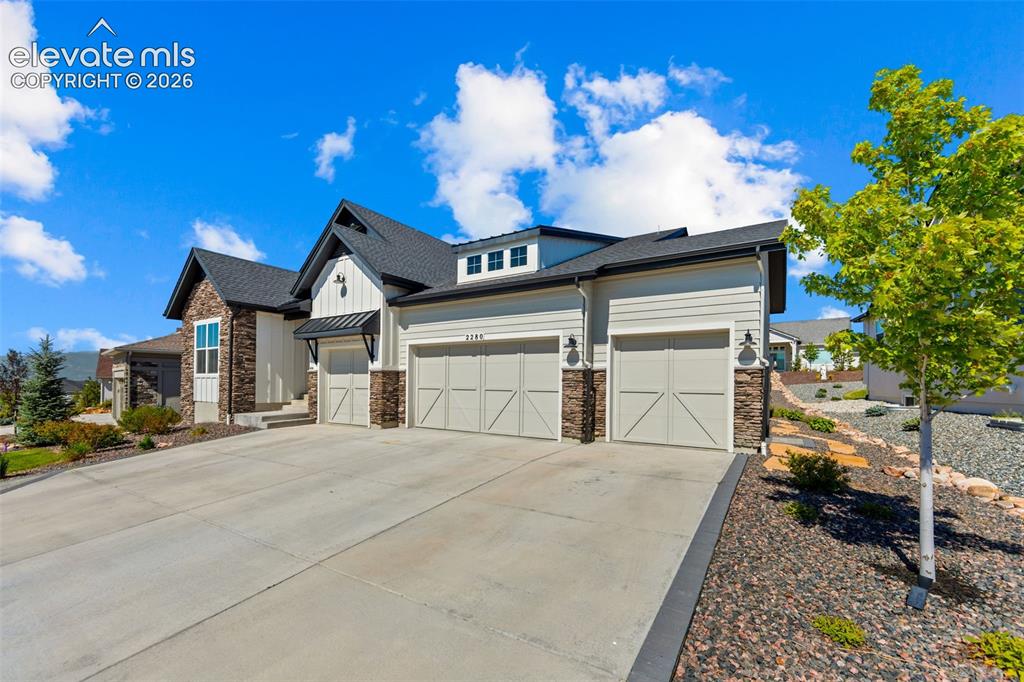 Image 5 of 32: Contemporary exterior featuring a stone and siding facade, a three-car gara